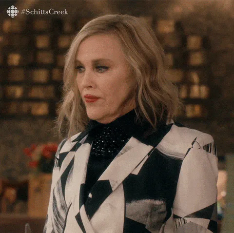 A woman in a black and white patterned blazer says 'I am suddenly overwhelmed with regret.'