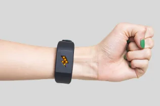 A wristband device with a lightning bolt icon sits on someone's forearm, fist clenched.