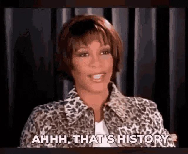A woman with a short bob and leopard print jacket smiles and points up, saying 'Ahhh, that's history.'