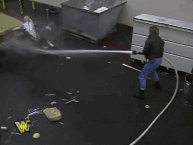 A worker tumbles into a large rolling bin while another worker watches.