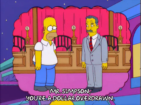 Homer Simpson stands before a man in a suit inside a bank, who says 'Mr. Simpson, you're a dollar overdrawn,' in a cartoon.
