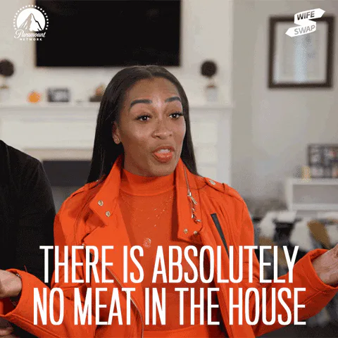 A woman in an orange jacket gestures animatedly in a living room and says 'There is absolutely no meat in the house.'