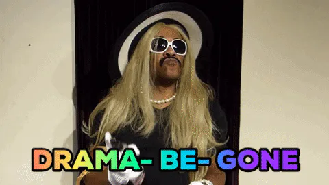 A performer in a blond wig, sunglasses and white gloves gestures as colorful text reads 'Drama be gone.'