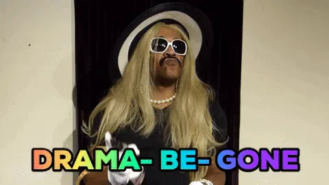 75dce93d-299f-c788-0474-675647372cb6.gif A performer in a blond wig, sunglasses and white gloves gestures as colorful text reads 'Drama be gone.'