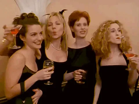 Sex+And+The+City+Friendship+GIF+by+Crave.gif Four women in black dresses toast with cocktails and laugh together.