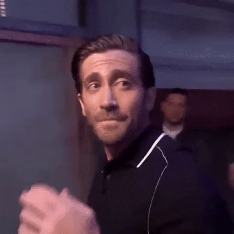 A man in a black polo shirt makes exaggerated faces and gestures before the shot fades to darkness.