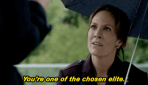 A woman under a black umbrella looks up and says 'You're one of the chosen elite.'