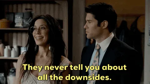 Side+Effects+Ghosts+GIF+by+CBS.gif A woman in glasses talks to a man in a suit in a rustic shop and says 'They never tell you about all the downsides.'