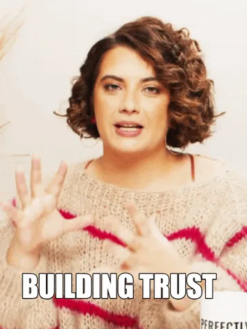 A woman with curly hair gestures while speaking, captioned 'Building trust.'