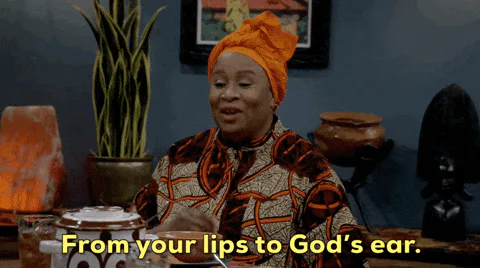 A woman in an orange head wrap smiles and says 'From your lips to God's ear.'