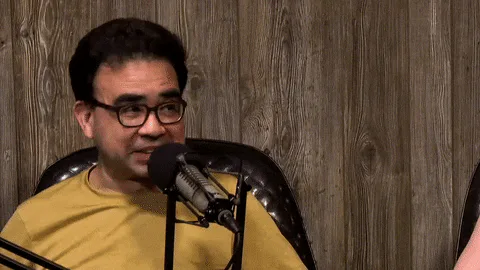 A man with glasses sits at a podcast microphone and says 'I can't talk about it.'