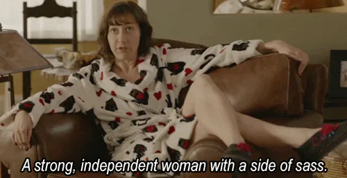 A woman lounges on a couch and says 'A strong, independent woman with a side of sass.'