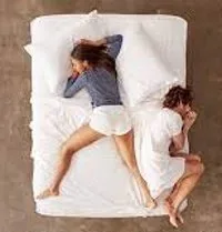 An overhead photo shows a couple lying in bed with their backs to each other, looking distant.