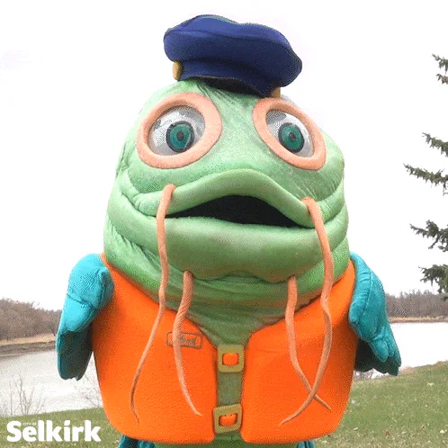 A green fish mascot in an orange vest and blue cap stares in shock, then the word 'What?' appears.