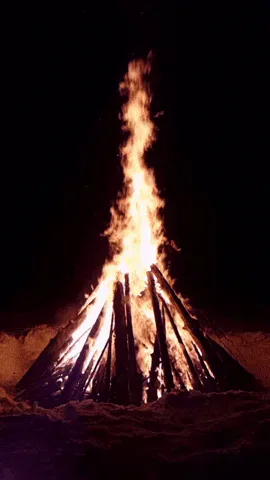 motion+bonfire+GIF.gif A tall bonfire burns against a dark night sky, its flames flickering upward.