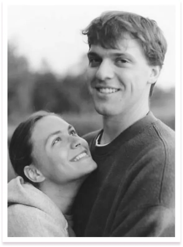 A cheerful black and white photo of a young couple, with the woman looking up affectionately at the smiling man, outdoors.