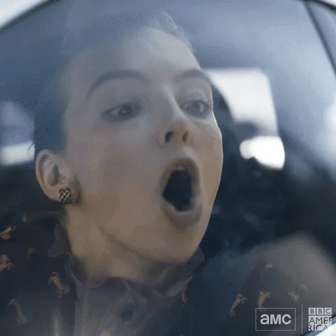 A woman inside a car reacts dramatically, then breathes on the window to write 'HELP' backward in the fog.
