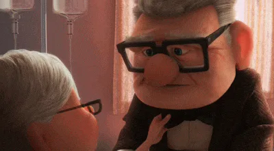 Two elderly animated characters face each other in a hospital-like room with IV bags visible in the background, as one gently touches the other's chest.