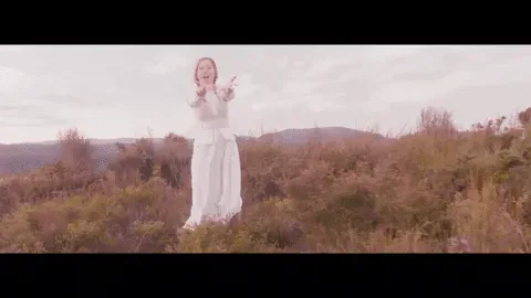 sound+of+music+dancing+GIF+by+Polyvinyl+Records.gif A woman in a white dress raises her arms and sings in a windswept field.