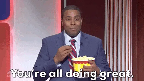 A man in a suit eats popcorn and says 'You're all doing great.'