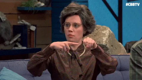 a28a50d9-8e83-1e10-5ed5-bde3349f2875.gif A woman with curly hair and glasses in a vintage dress makes an exaggerated pointing hand gesture.