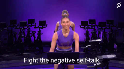 A fitness instructor on a stationary bike says 'Fight the negative self-talk, the judgements, the intolerance.'