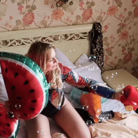 Bored+Party+Girl+GIF+by+Karo+Glazer.gif A woman in a sequined jacket lounges on a bed with a watermelon float and bubbles and says 'I just wanna have fun.'