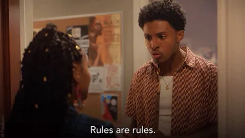 Season+4+Reaction+GIF+by+grown-ish.gif A young man with curly hair talks to a woman with braided hair in a hallway and says 'Rules are rules.'