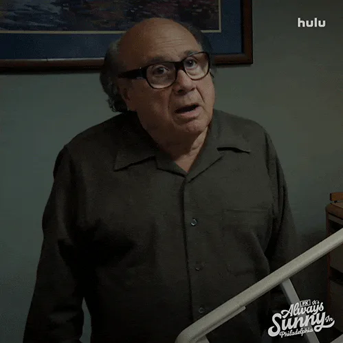 A bald man in glasses and a dark shirt says 'Can you be more specific?'