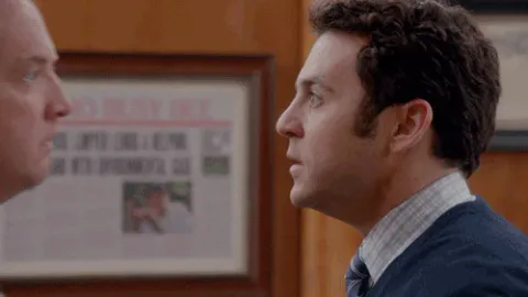 8e01b131-d9d8-9027-866d-24cf29cb7fca.gif Two men in suits stand close together in profile, facing each other in a tense exchange.