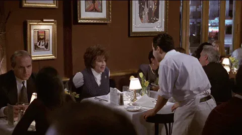 Eating+Alone+First+Wives+Club+GIF+by+NicholeBeyrooty.gif A waiter greets a woman dining alone at a restaurant table, captioned 'By Yourself?' 'Si.'