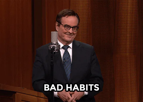 A man points to his cheek and says 'Bad habits' at a microphone.