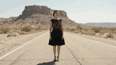 Apps 2026 tumbleweed gemini 4 A woman in a black dress watches a tumbleweed roll across an empty desert road.