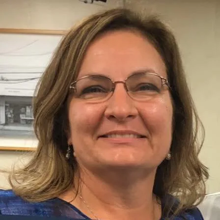 image.png A woman with glasses smiling in an indoor setting.