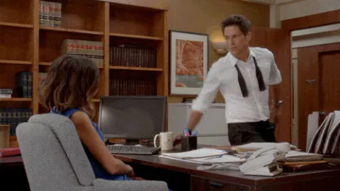 Mad+Rob+Lowe+GIF+by+The+Grinder.gif A man reaches across a desk, sending papers flying, as a seated woman looks on.