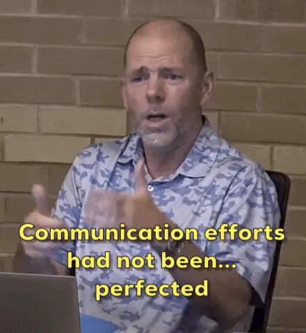 A bald, bearded man in a blue camouflage shirt gestures and says, 'Communication efforts had not been... perfected.'