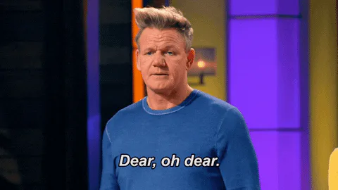 A man in a blue sweater winces and says 'Dear, oh dear.'