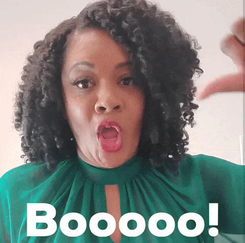 A woman with curly hair gives a thumbs down and shouts 'Booooo!'