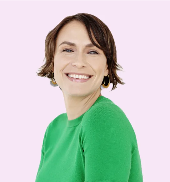 Image-12.png Laurie Gerber smiles in a green top against a solid pink background.