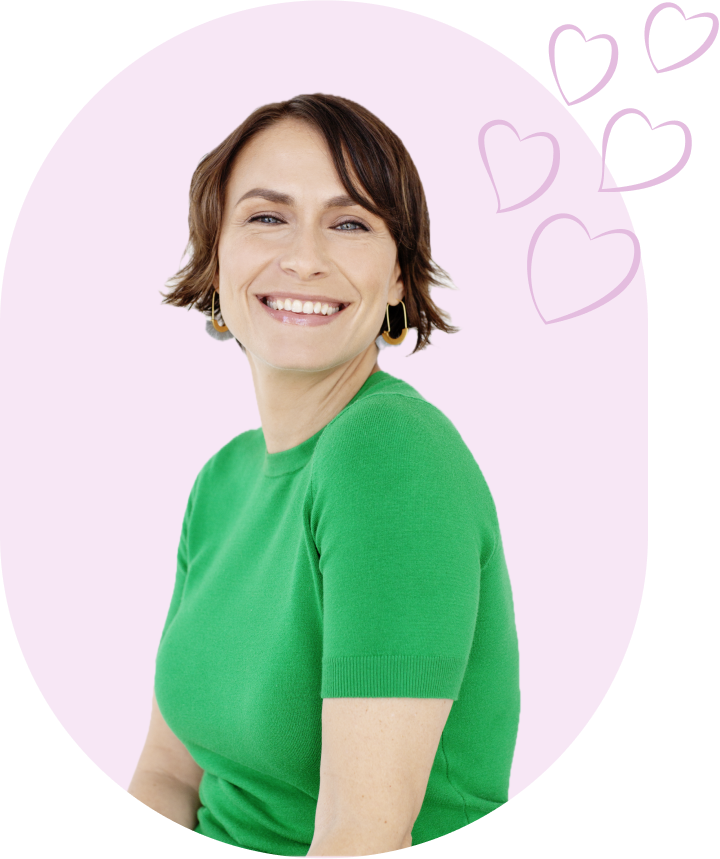 Smiling woman in green shirt with illustrated hearts on pink background.
