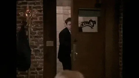 norm+GIF.gif A man in a suit walks through a doorway into a bar, then the scene cuts to a bartender and seated patrons at the bar counter.