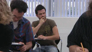 A student in a classroom writes 'You can do it!' on his palm while classmates sit nearby with notebooks.