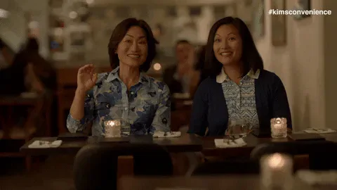double+date+wave+GIF+by+Kim's+Convenience.gif Two women wave and smile together at a candlelit restaurant table.