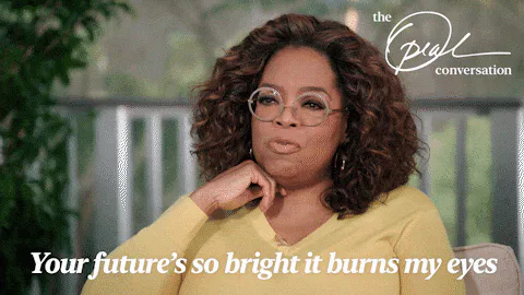 A smiling woman in glasses rests her chin on her hand; text reads 'Your future's so bright it burns my eyes.'