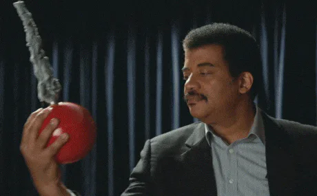 A man in a lecture hall swings a heavy ball toward his own face, then smiles as the word 'SCIENCE' appears.