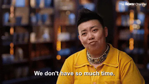 A woman with short dark hair in a yellow jacket and layered necklaces says 'We don't have so much time.'