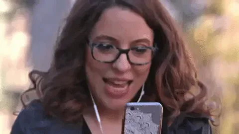 GIF+by+SoulPancake.gif A curly-haired woman in glasses gasps with delight at her phone.