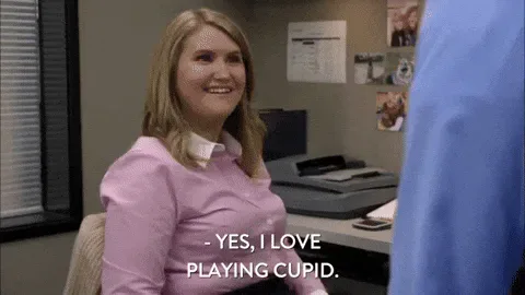 Comedy+Central+Cupid+GIF+by+Workaholics.gif A smiling woman in a pink shirt says, 'Yes, I love playing cupid.'