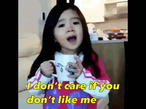 A little girl holding a mug says 'I don't care if you don't like me. I love me.'