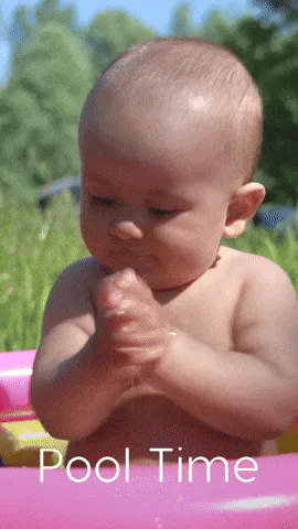 A laughing baby claps and sticks out her tongue in a pink inflatable pool, captioned 'Pool Time.'